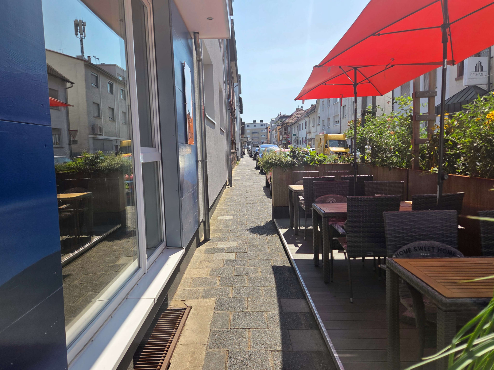 Sonnige Terrasse mit roten Schirmen vor dem Café Elisa