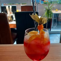 Fruchtiger Aperitif mit Orange und Physalis im Glas